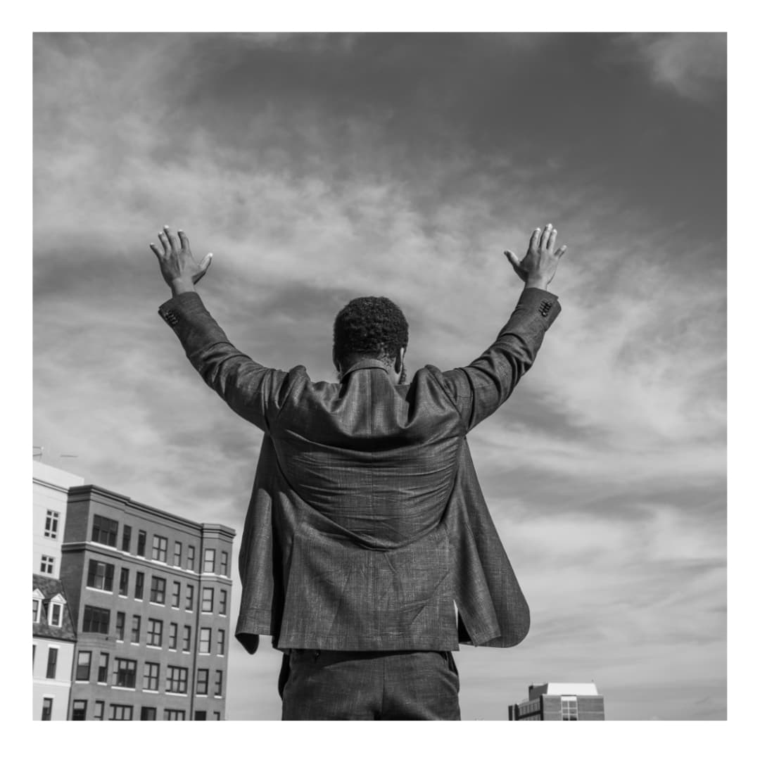 Portrait of Halim Flowers with arms raised.